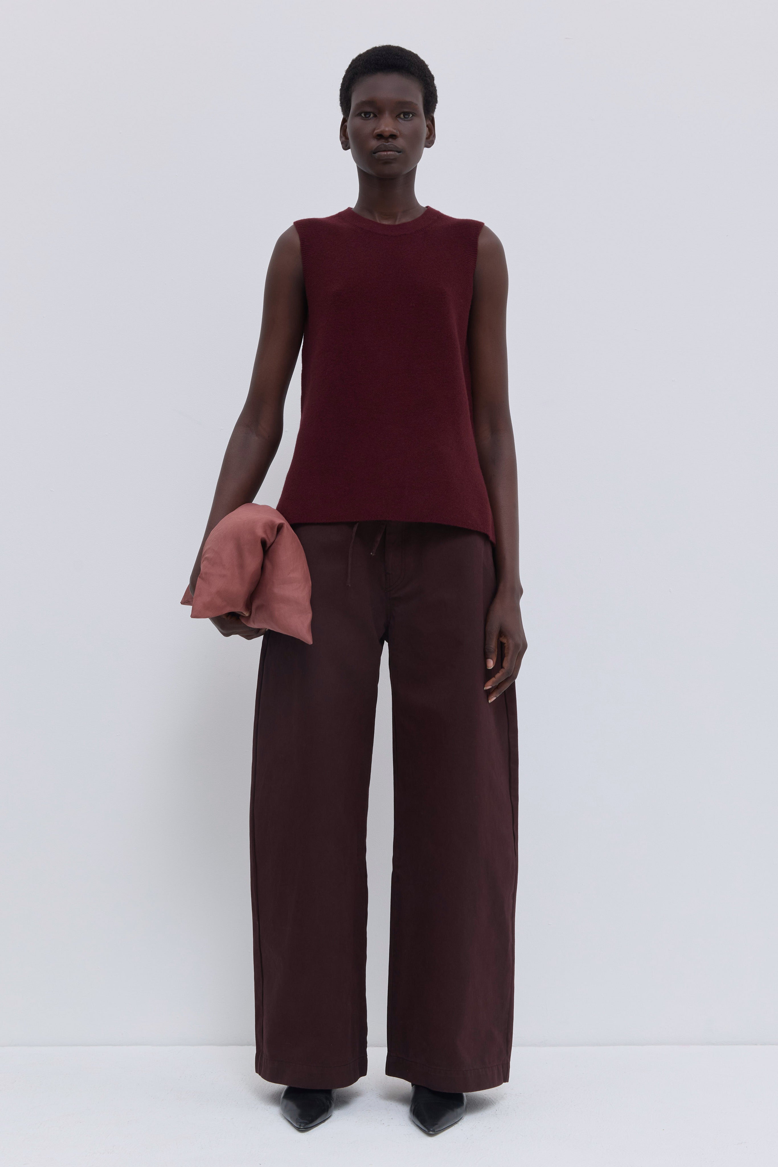 Garnet sleeveless wholegarment knit top with round neckline and side slits.