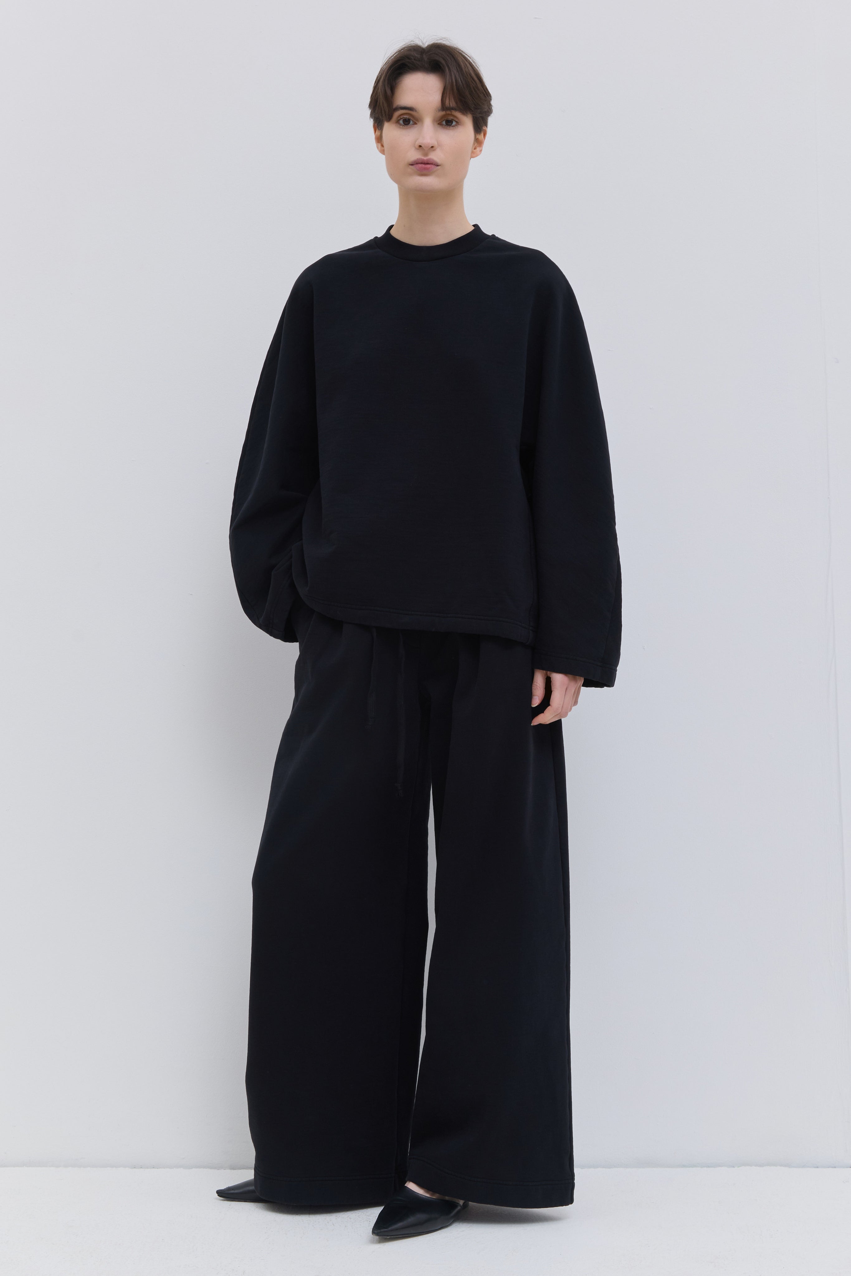 Front view of black wide-leg jersey sweatpants with drawstring waist.