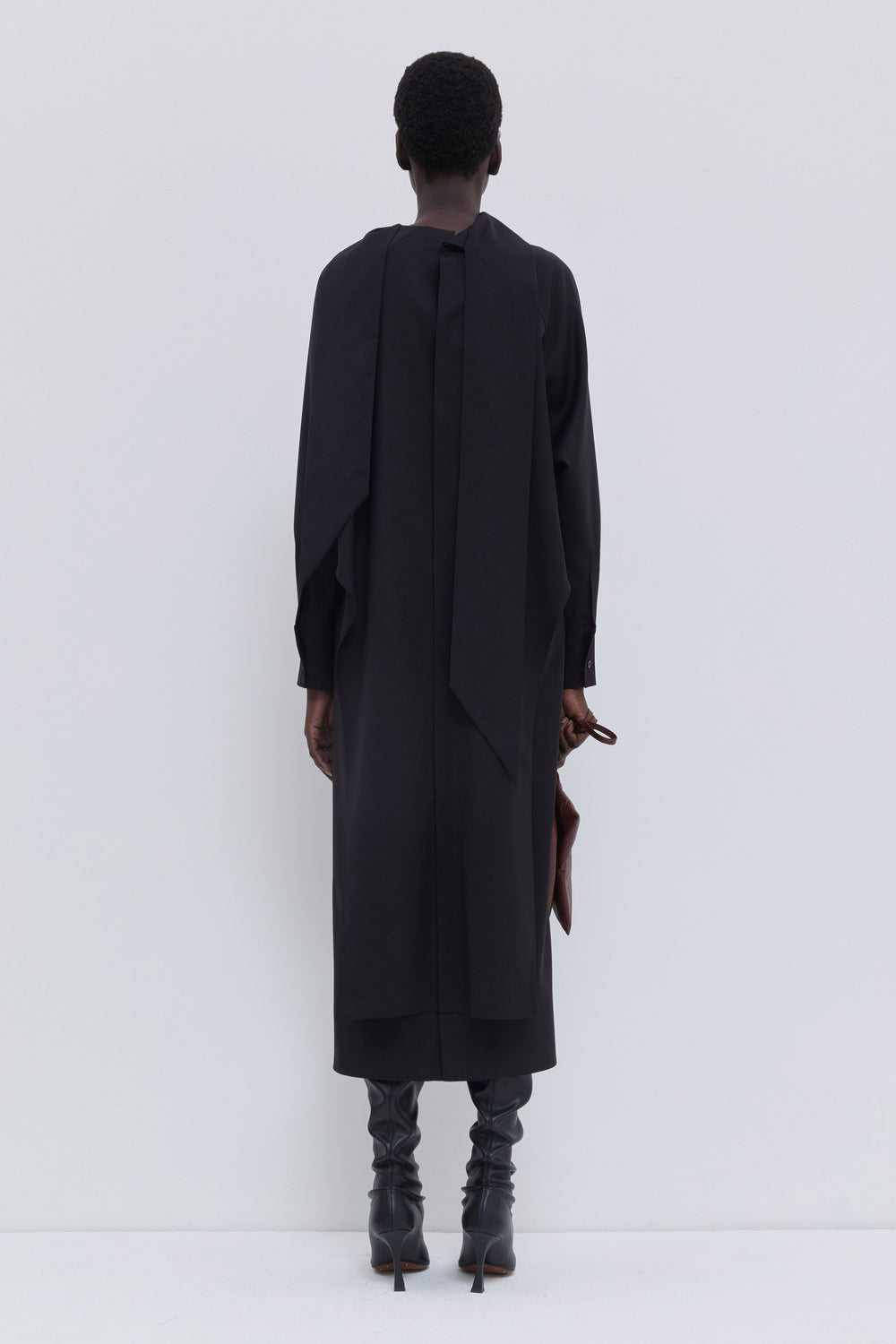 Back view of a black virgin wool dress with integrated scarf detail.
