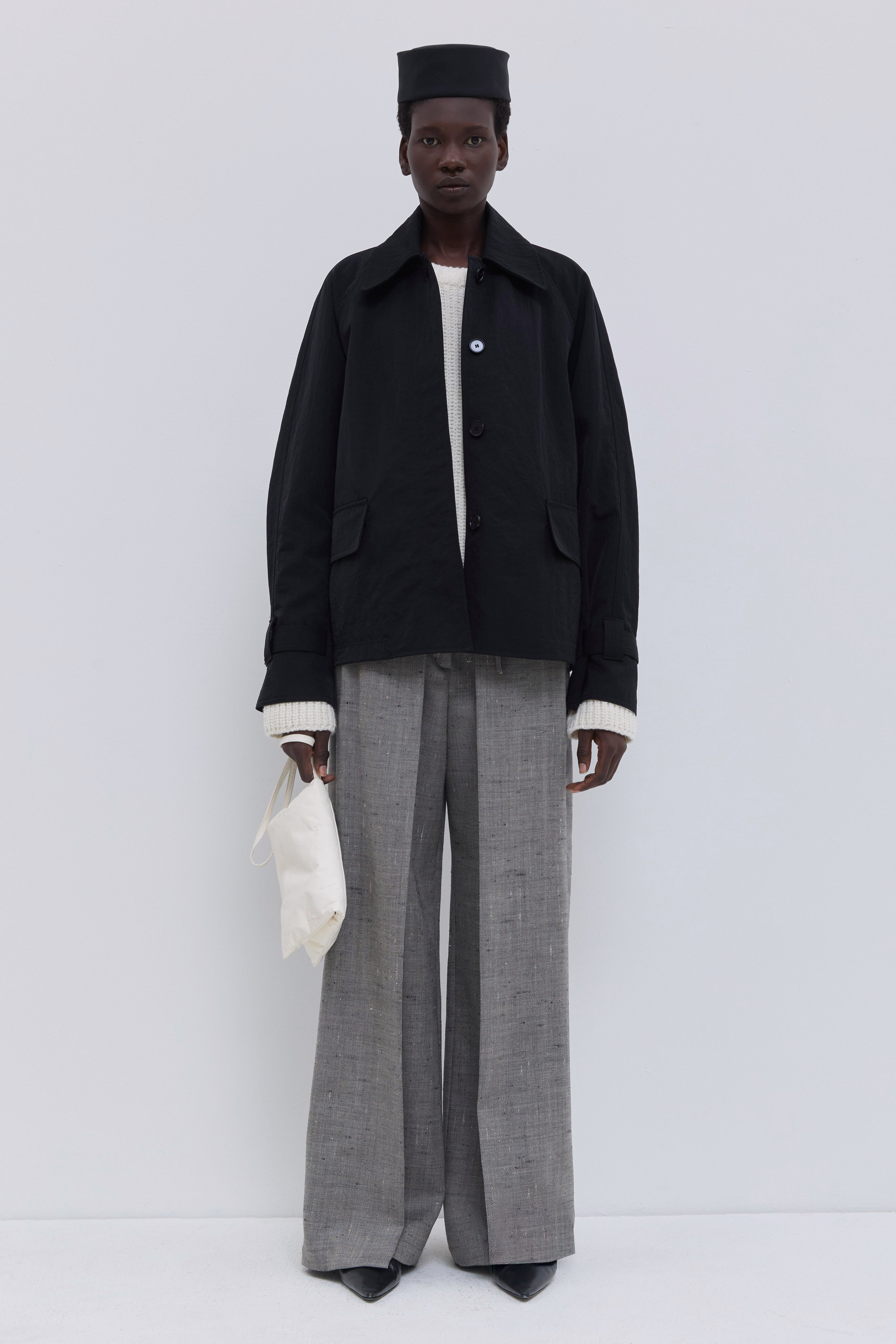 Black raglan-sleeve jacket with a classic collar and oversized flap pockets.