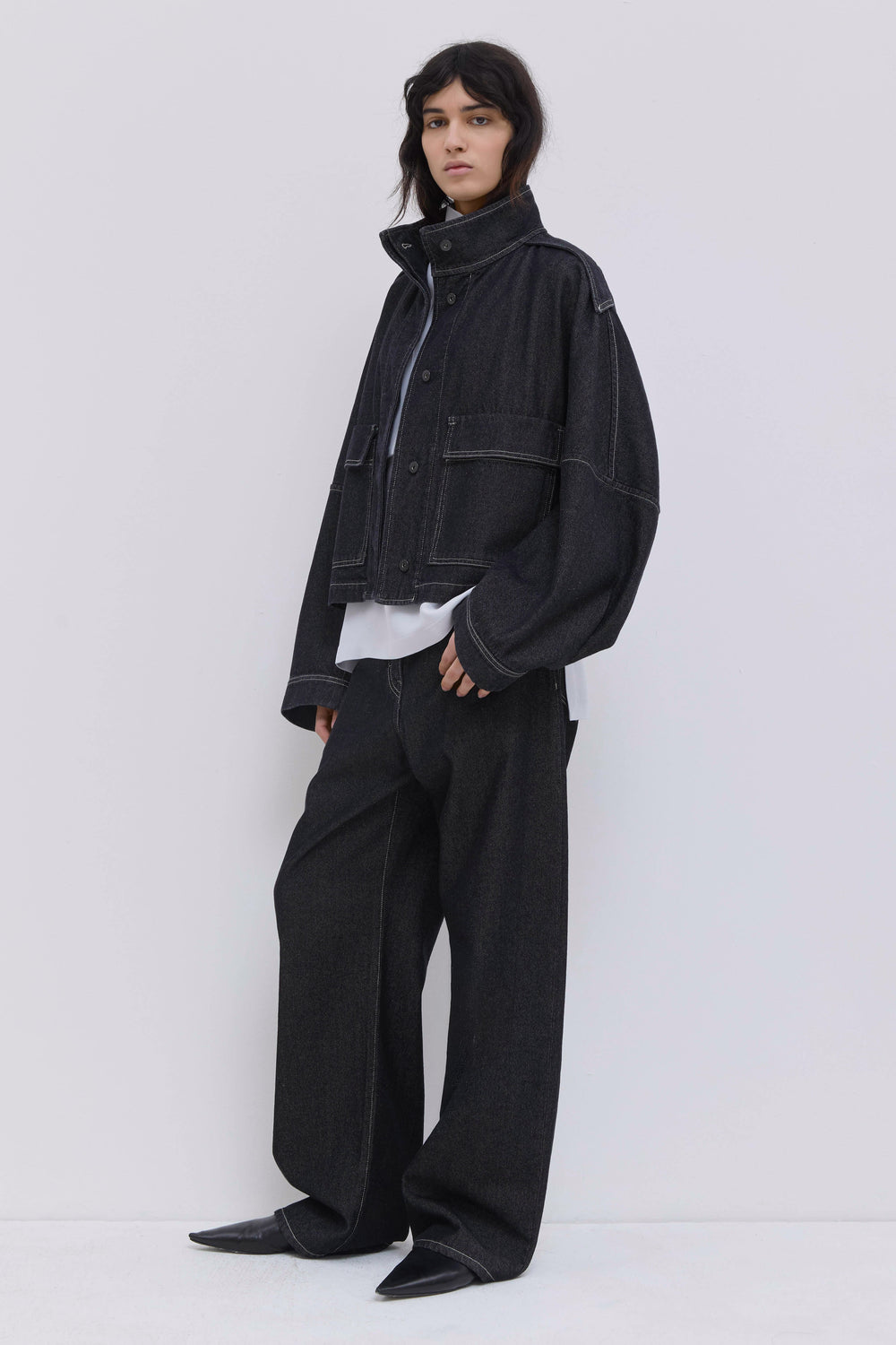 Back view of a cropped raw denim jacket with relaxed silhouette.