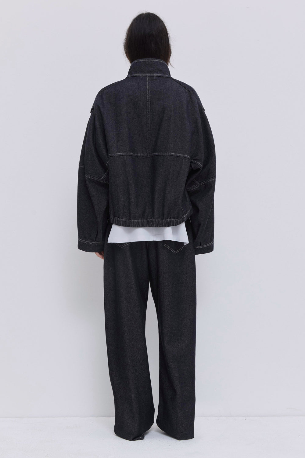 Luxury cropped denim jacket in raw dark denim with oversized sleeves and utility pockets.