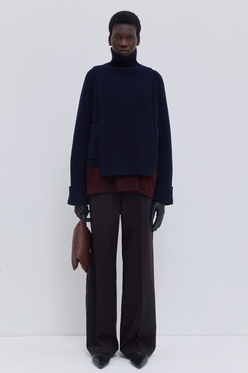 Dark marine ribbed merino wool and cashmere knit bib layered beneath a matching ribbed cardigan with tailored trousers.