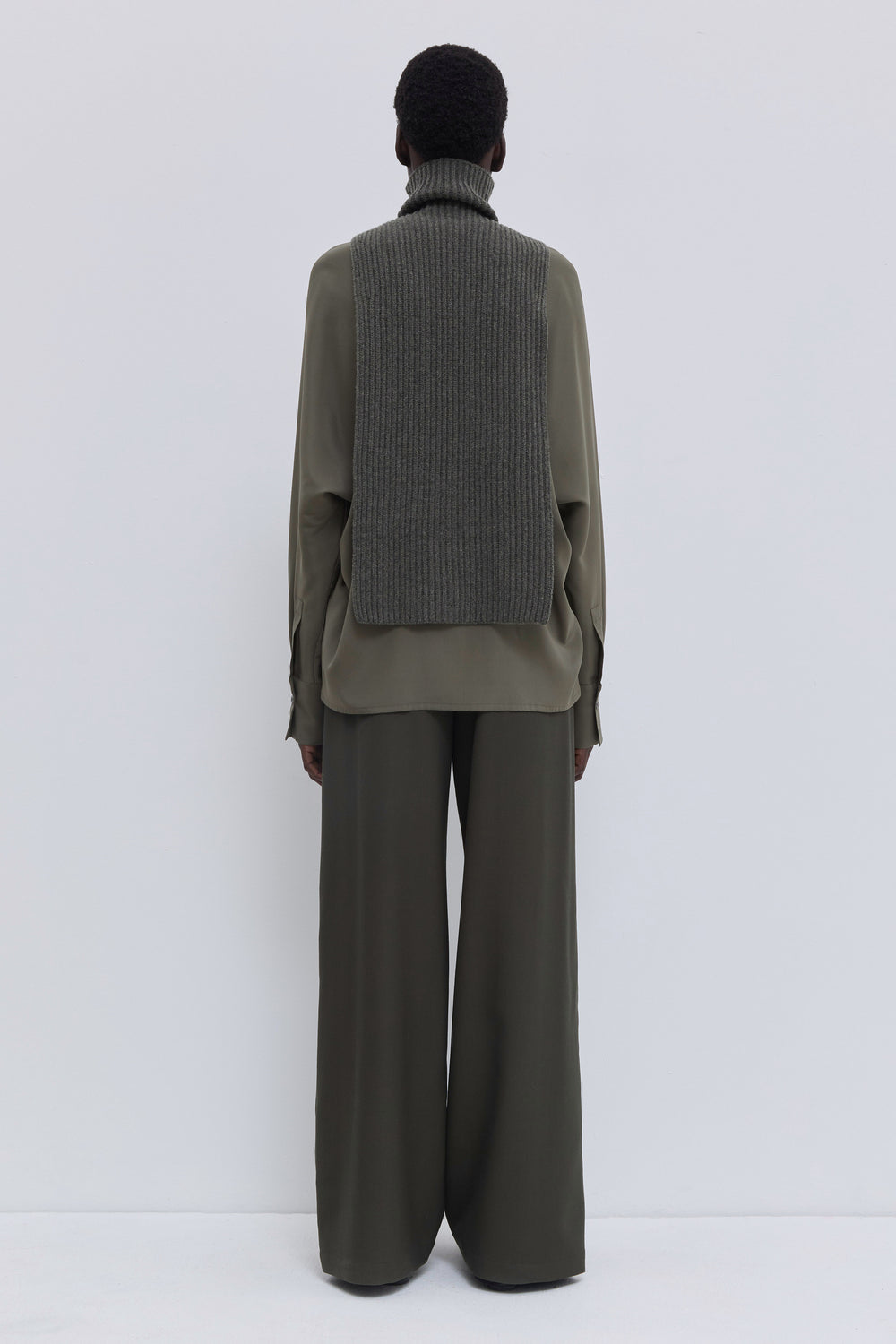 Forest melange ribbed merino wool and cashmere knit bib with high ribbed turtleneck layered over an olive blouse.