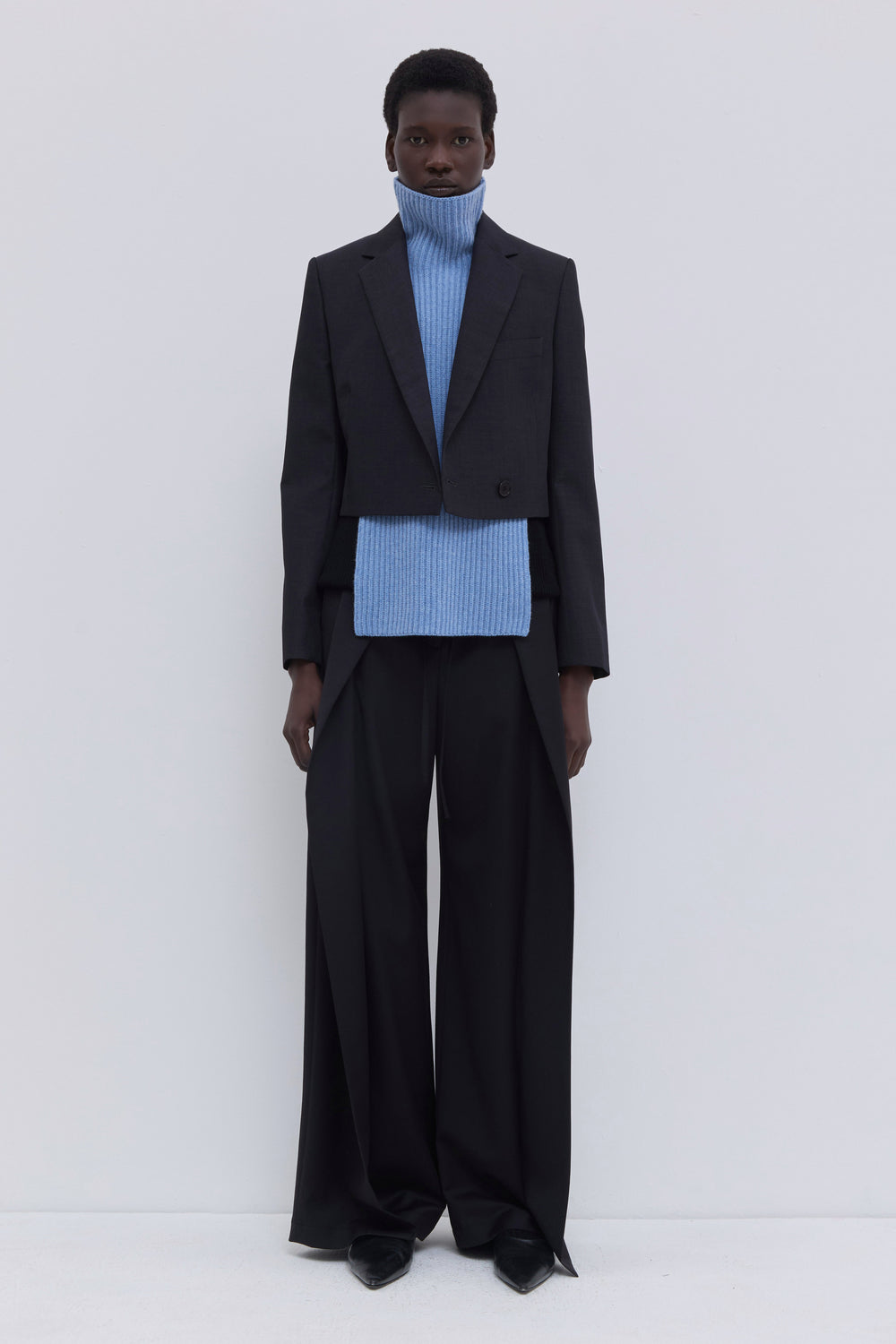 Mirage blue ribbed merino wool and cashmere knit bib with oversized turtleneck styled with tailored wide-leg trousers.