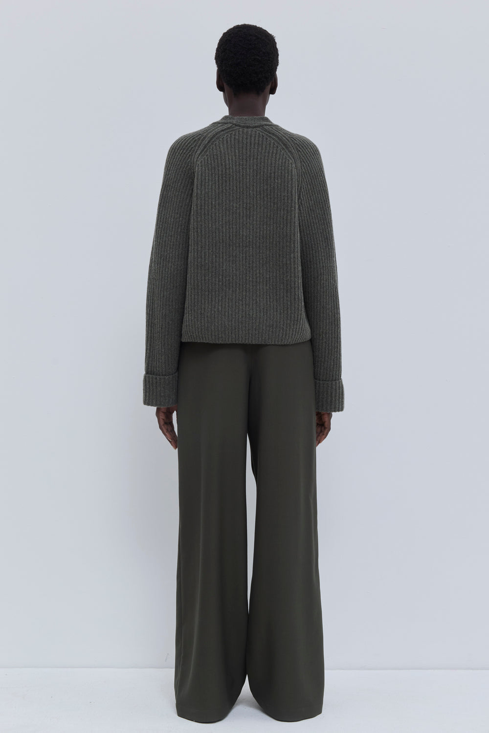 Front view of the forest melange ribbed merino wool and cashmere V-neck sweater styled with tailored trousers.