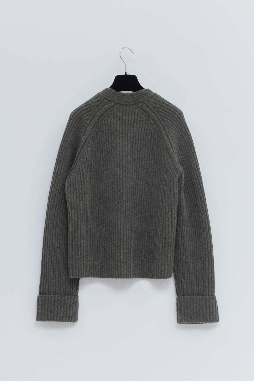 Angled view of the forest melange ribbed merino wool and cashmere V-neck sweater with tailored trousers.