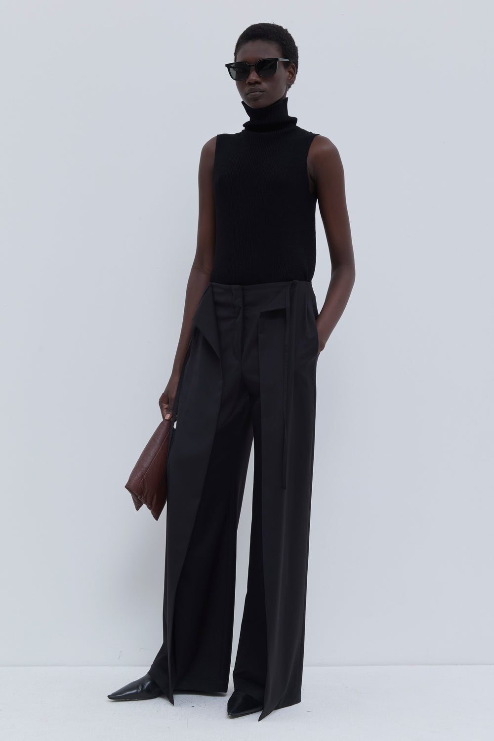 Three-quarter view of the Paire wide-leg trousers in black styled with a sleeveless ribbed turtleneck.