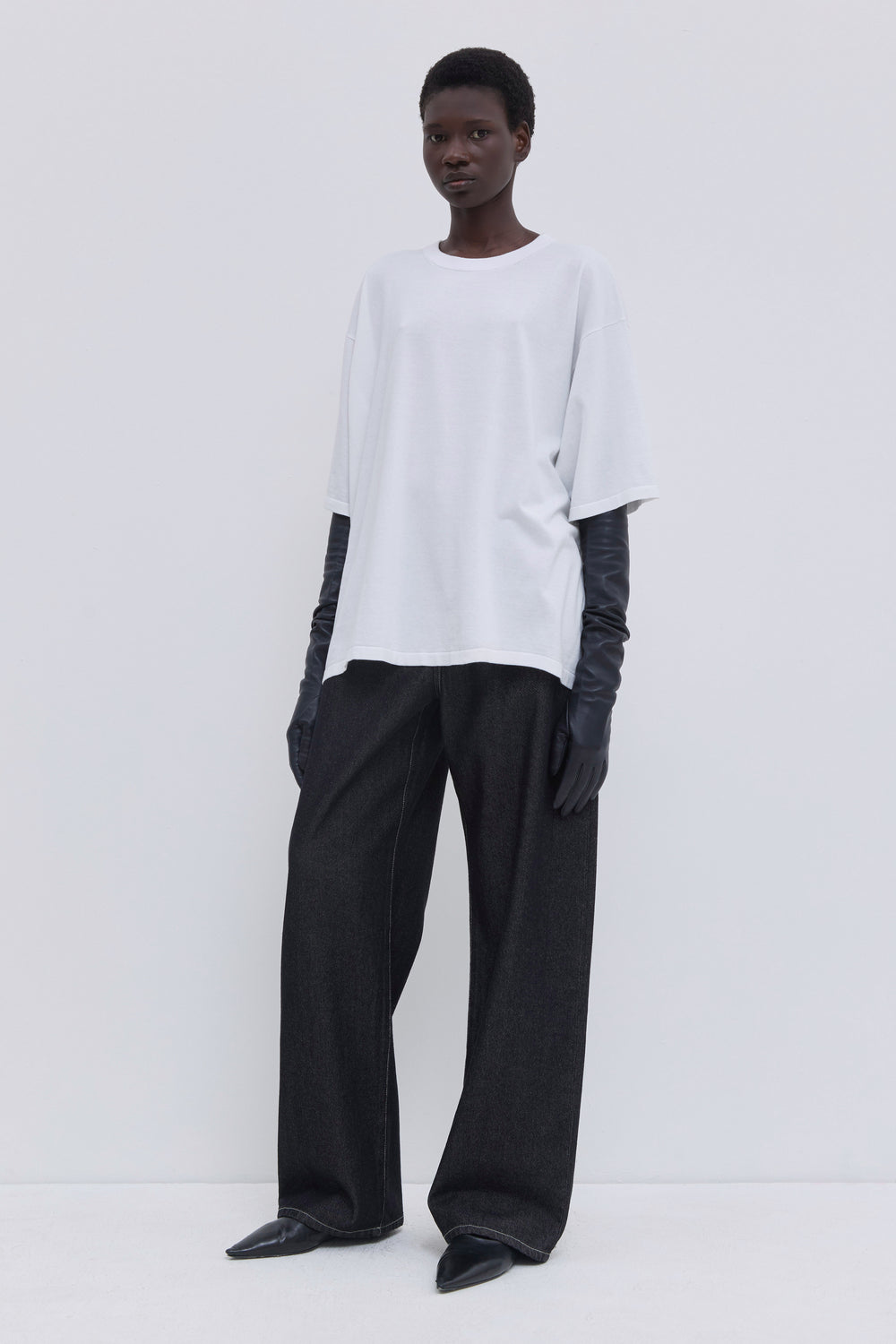 Side view of dark raw denim jeans with contrast topstitching and wide legs.