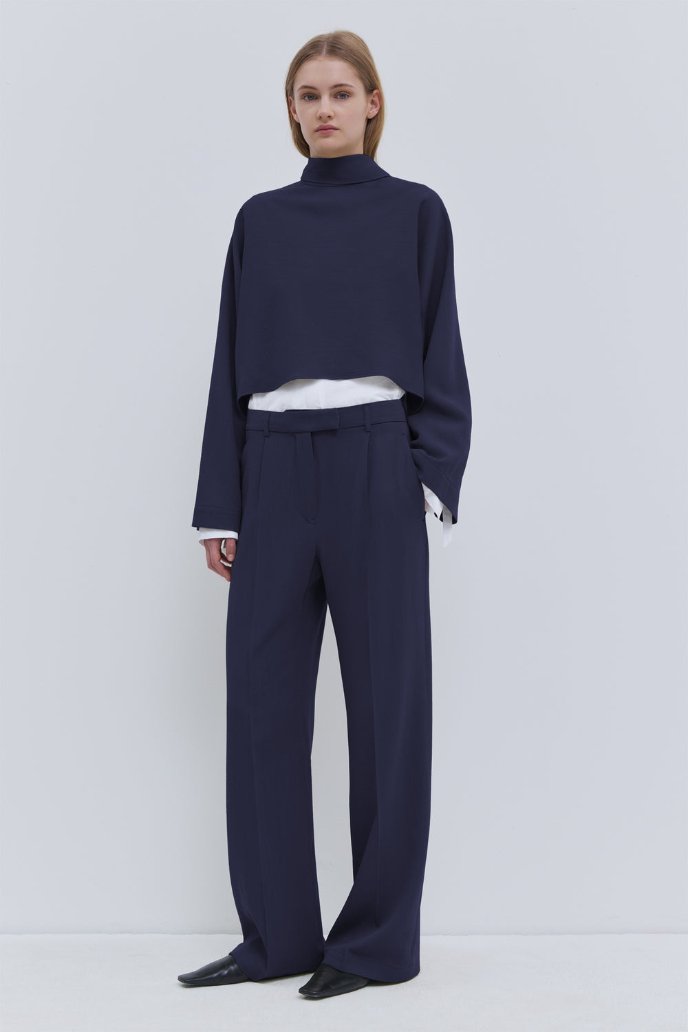 Tesos dark navy wool cropped top with asymmetrical scarf detail and long sleeves.